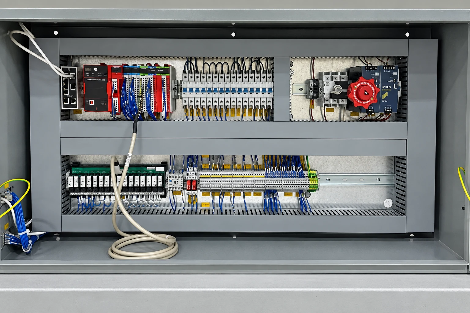 Open control panel showing the PLC, circuit breakers, relays, and labeled terminal wiring